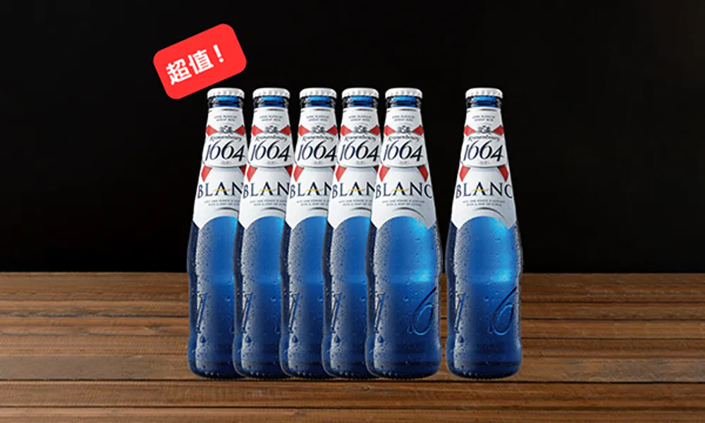 Six 1664 Blanc beer bottles lined up on wood, blue bottles with condensation, red "Great Value" tag at top left, black background